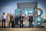 Grupa ludzi pozuje na tle wiekiego napisu wolnostojącego ‘EXPO 2020”.