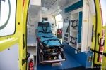 Środek ambulansu. Na środku pojazdu stoi pusty niebieski fotel dla pacjentów. 