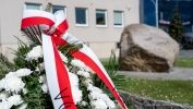 Kwiaty z wstęga biało czerwoną na tle pomnika rocznicy chrztu Polski 
