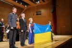 Czwórka ludzi na scenie. Dwójka trzyma flagę Ukrainy.