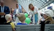  Kobieta podaje baloniki i smycze dzieciom na lotnisku. 