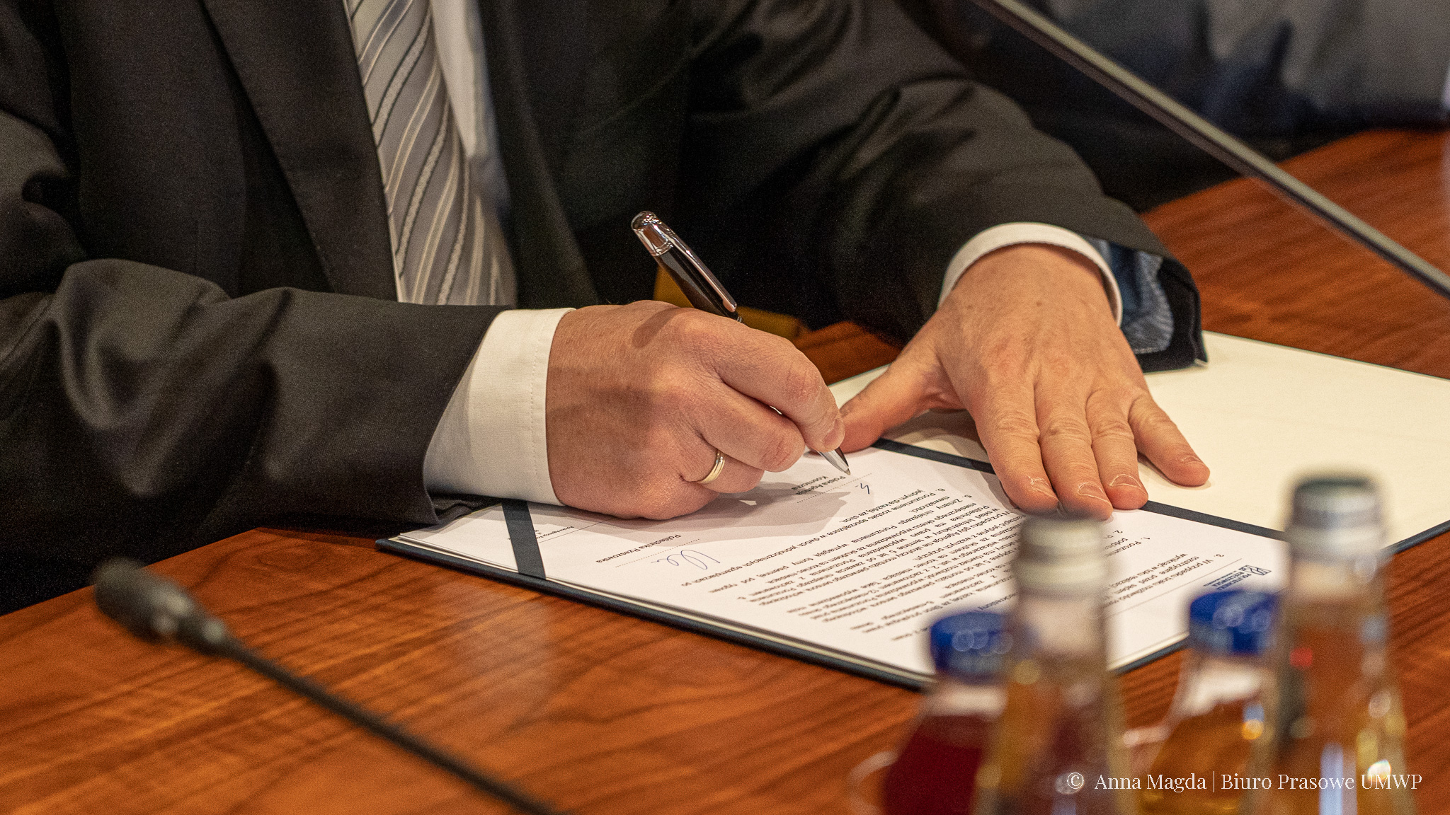 Zdjęcie rąk podpisujących dokument piórem.